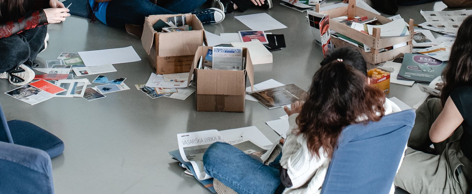 Rankos, dėžės ir popieriaus lapai ant grindų per dirbtuves
